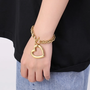Close-up of gold chain bracelet with large heart pendant and T-bar toggle on wrist