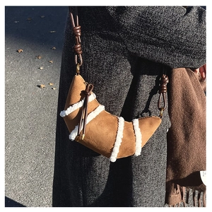 Close-up of brown suede croissant bag with faux shearling stripes and woven strap detail