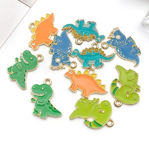 Gros plan de breloques dinosaures en émail coloré vert, orange et bleu pour bijoux