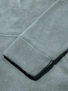 Dettaglio macro del tessuto in pile grigio-blu e delle cuciture sul polsino della manica
