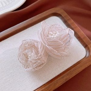 Detailed view of handmade mesh flower earrings with layers and center pearl accents
