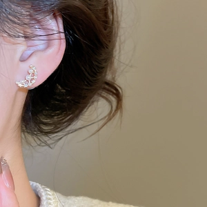 Close-up of gold-plated crescent moon earrings with inlaid pearls and zircon stones
