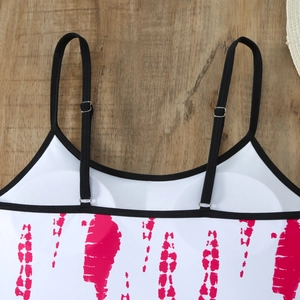 Detail of adjustable black shoulder strap with silver buckle on pink tie-dye swimwear top