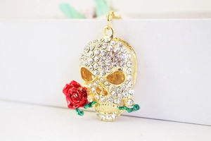 Macro shot of gold-plated skull keychain with red enamel rose and sparkling rhinestones