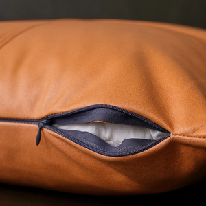 Detailed close-up of brown faux leather pillow cover showing a hidden zipper and fabric texture