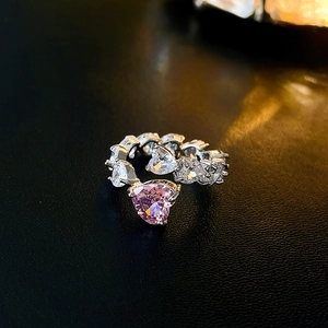 Macro shot of silver adjustable ring with pink heart zircon on black leather background