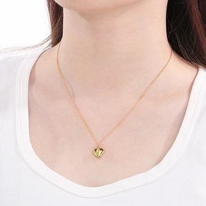 Minimalist gold heart pendant necklace for women worn on a model with white background