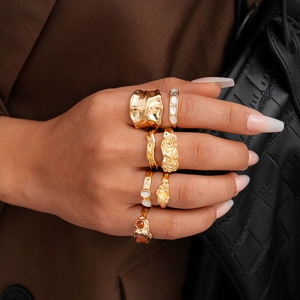Close-up of seven vintage gold-plated rings with resin and pearls on a model's hand