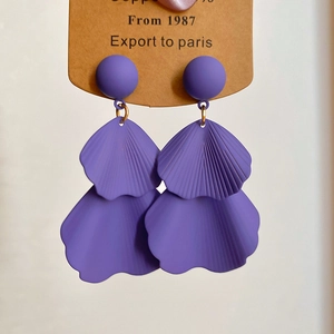 Close-up of deep purple matte petal tassel earrings hanging on a display card