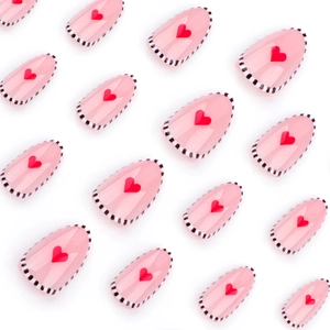Faux ongles amande roses avec motif cœur rouge et bordure pointillée noire et blanche