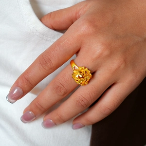 Detailed macro view of 24k gold-plated floral cluster ring on a model's hand