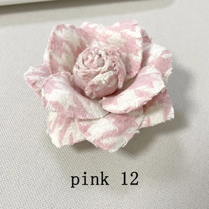 Macro shot of pink and white herringbone pattern camellia brooch with frayed edges
