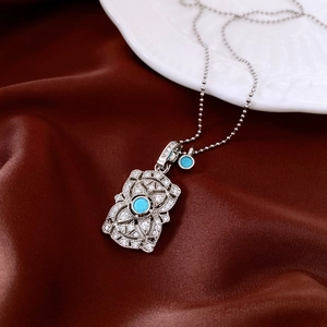 Detail of vintage silver pendant with turquoise stone on dark brown satin fabric