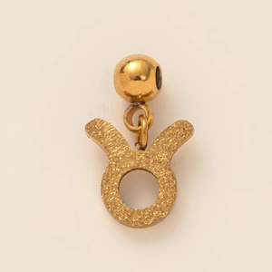 Macro view of gold-plated Taurus zodiac pendant with a textured matte finish