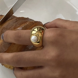 Dettaglio macro di un anello vintage largo dorato con inserto di perla bianca