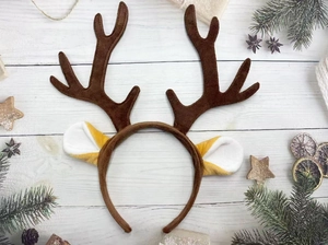 Close-up of brown plush reindeer antler headband on wooden background with Christmas decor