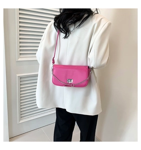 Detail shot of the silver chain and metallic turn-lock closure on rose pink leather bag