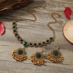 Luxury vintage jewelry set with green gemstones and pearls on a rustic wood background