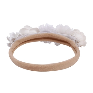 Close-up of baby headband with white satin fabric flowers and tulle petals on nude band