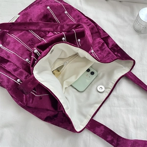 Detail view of purple velvet tote bag with pearl accents and spacious inner pocket