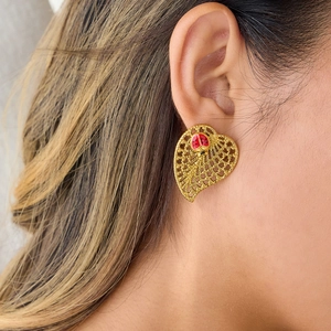 Elegant gold leaf earrings with ladybug detail worn by a model in a warm setting