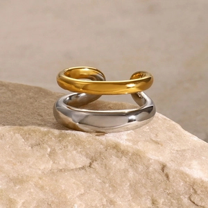 Detailed macro shot of two-tone gold and silver interlocking open ring on beige stone