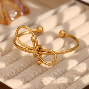 Gros plan d'un bracelet jonc à nœud doré dans un écrin en velours beige élégant