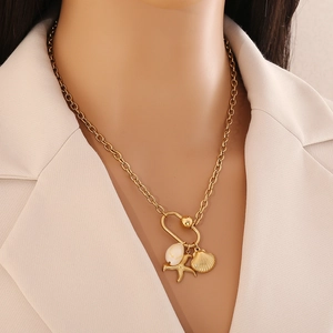 Detail of gold necklace featuring starfish, seashell, and gold bead charms on a model