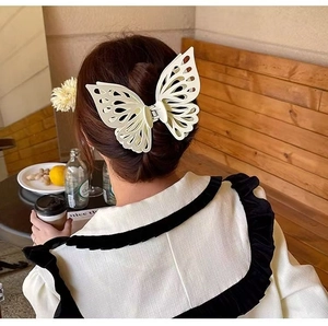 Detail view of a large cream white butterfly hair claw clip worn on long wavy hair