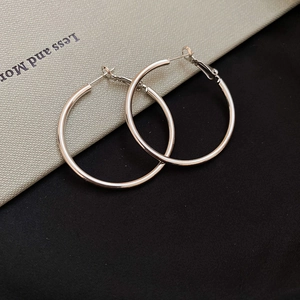 Detailed close-up of silver hoop earrings with polished finish and hinged clasp