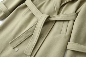 Detailed macro view of wool coat texture showing the belt knot and button craftsmanship