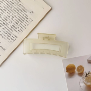 Close-up of a large matte pale yellow square hair claw clip on a clean white surface