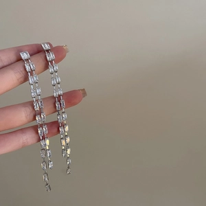 Détail de boucles d'oreilles pendantes argentées avec zircons étincelants