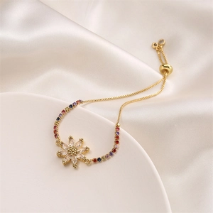 Macro view of gold sunflower bracelet with colorful cubic zirconia on white silk