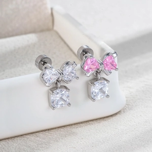 Elegant silver bow stud earrings with pink and white zircons on a jewelry tray
