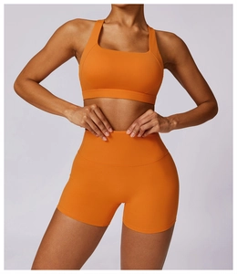 Detail of high-waist orange yoga shorts and square neck sports bra in seamless knit