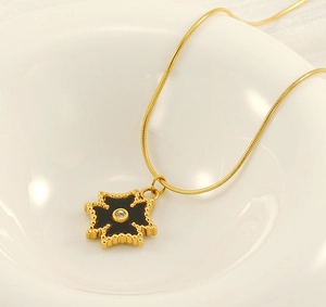 Macro detail of gold tarot cross pendant with black enamel and zircon on snake chain