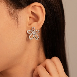 Detailed view of elegant silver floral earrings with zircon stones on a model