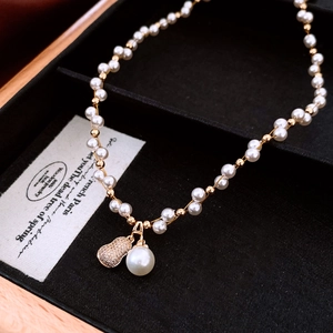 Detailed shot of pearl necklace with gold-plated bead accents and shimmering crystal pendant