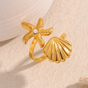 Detail of 18K gold-plated starfish and shell open ring with zircon on sand background