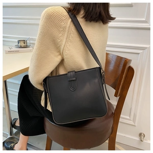 Chic black bucket bag with a wide strap shown in a minimalist lifestyle setting