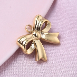 Close-up of a golden bowknot pendant crafted from 304 stainless steel on pink silk