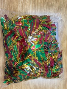 Macro detail of red green and gold metallic Christmas tinsel inside transparent packaging