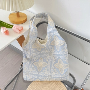 Détail d'un sac cabas en coton bleu clair avec broderie papillon et fleurs blanches