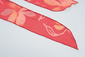 Détail du tissu en mousseline rouge à fleurs avec ourlet à volants et bords surjetés