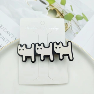 Detail of three cream cat-shaped acetate hair clips on a white display card in a ceramic dish