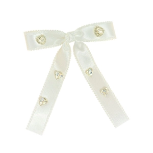Detail view of white satin bow hair clip with lace edges and heart-shaped rhinestones