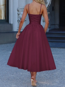 Detail of elegant burgundy midi dress featuring a stylish back lace-up design