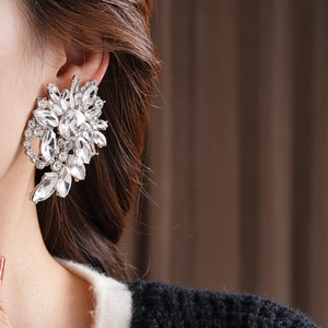 Close-up of sparkling flower-shaped crystal statement earring on model's ear