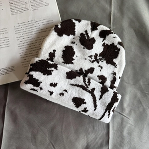 Close-up of knit texture on cow print beanie with stylish white and brown patterns